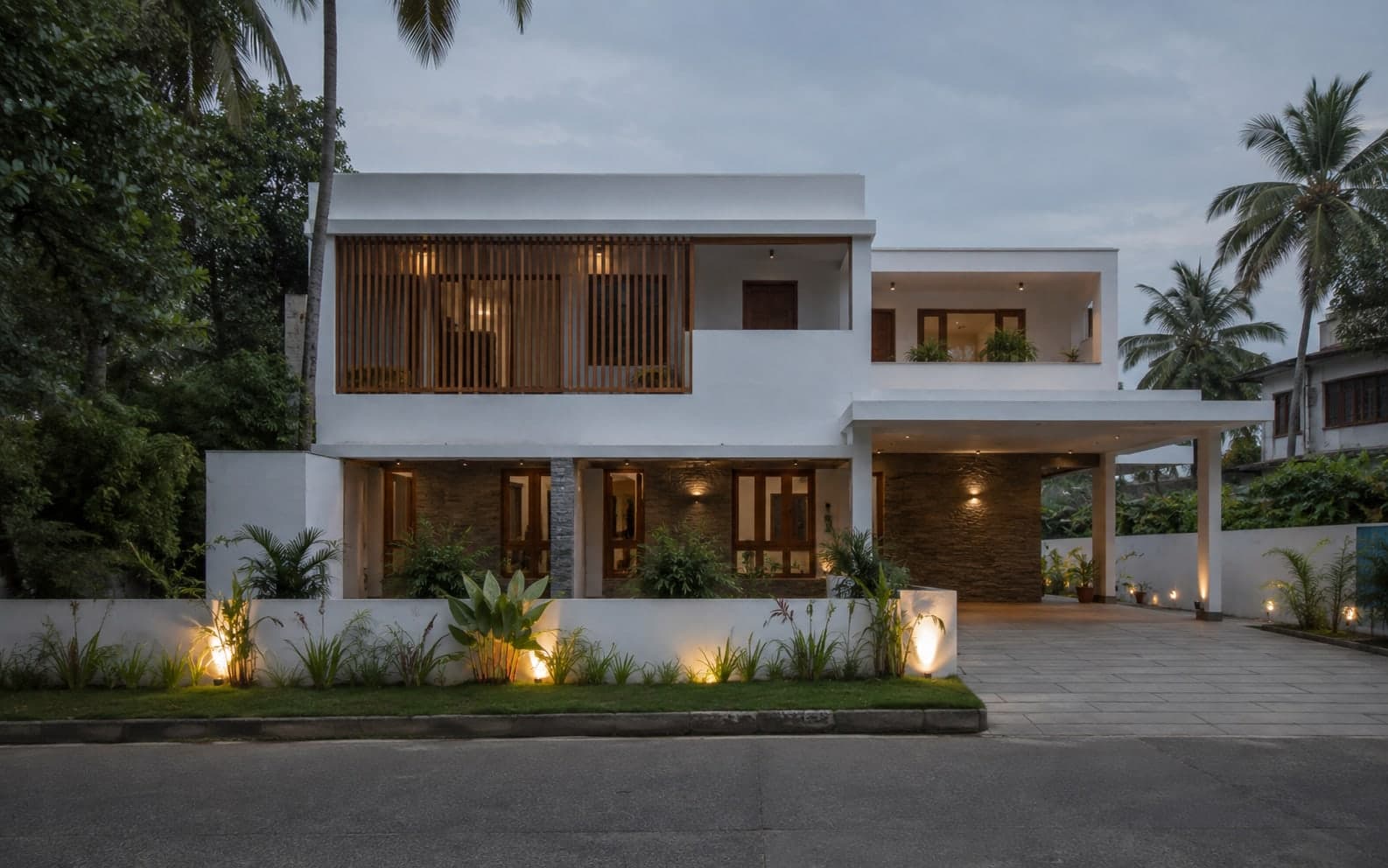 Contemporary two-storey villa with illuminated entrance and landscaped garden